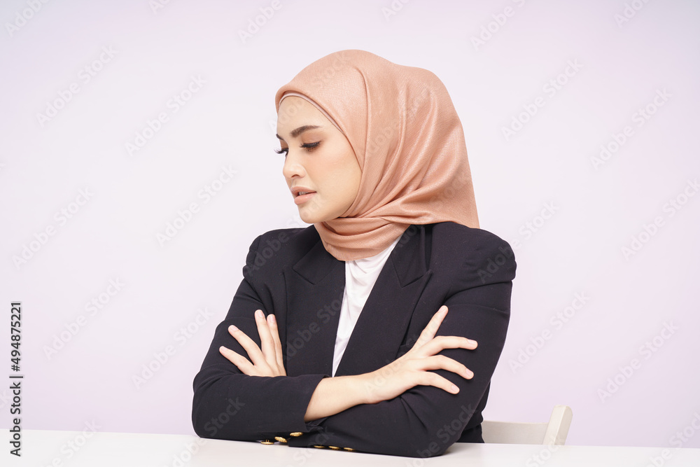 A beauty shot of a pretty young Asian hijab corporate girl with smooth glowing skin smiling and relaxing on a table over white background studio. Beauty skin care, office concept. A beauty shot of a pretty young Asian hijab corporate girl with smooth glowing skin smiling and relaxing on a table over white background studio. Beauty skin care, office concept.