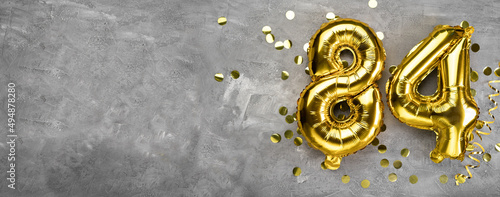 Yellow foil balloon number, number eighty four on a concrete background. Greeting card with the inscription 84. Anniversary concept. for anniversary, birthday, new year celebration. banner, © mtrlin