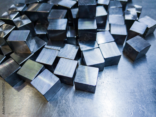 pile of small machined shiny steel cubes on metal surface photo