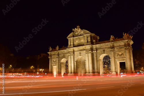The Puerta de Alcala in Madrid at night. With flashes and lights of cars passing by. Famous monument of the Spanish capital.