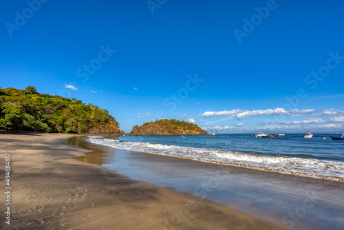 Fototapeta Naklejka Na Ścianę i Meble -  Playa Ocotal with Pacific ocean waves on rocky shore, El Coco Costa Rica. Famous snorkel beach. Picturesque paradise tropical landscape. Pura Vida concept, travel to exotic tropical country.