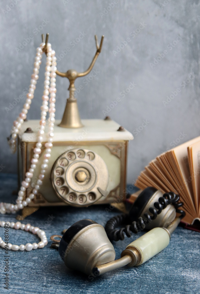 Vintage phone, open book, old keys, and retro pocket watch on a desk. Nostalgic composition image. 
