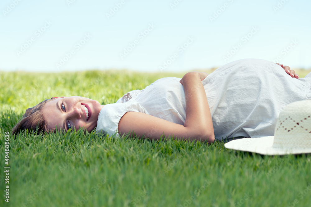 Shes counting down the days. A pretty woman lying on the grass outdoors and relaxing in the sunshine. Shes counting down the days. A pretty woman lying on the grass outdoors and relaxing in the sunshine.