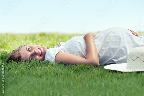 Shes counting down the days. A pretty woman lying on the grass outdoors and relaxing in the sunshine.