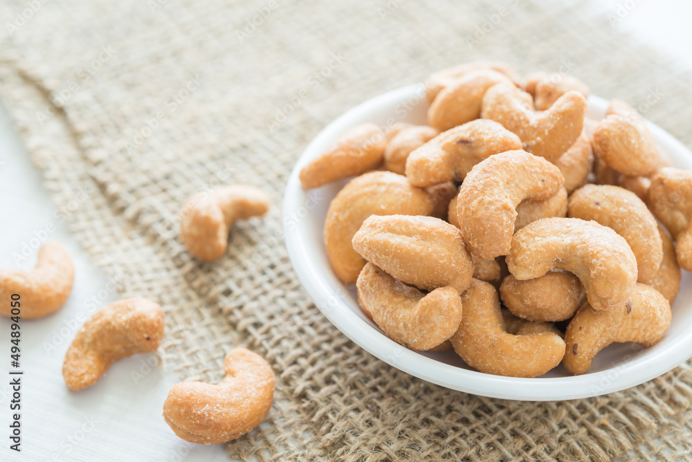 Salted cashew nuts in dessert bowl on sackcloth background. Food concept. Salted cashew nuts in dessert bowl on sackcloth background. Food concept.