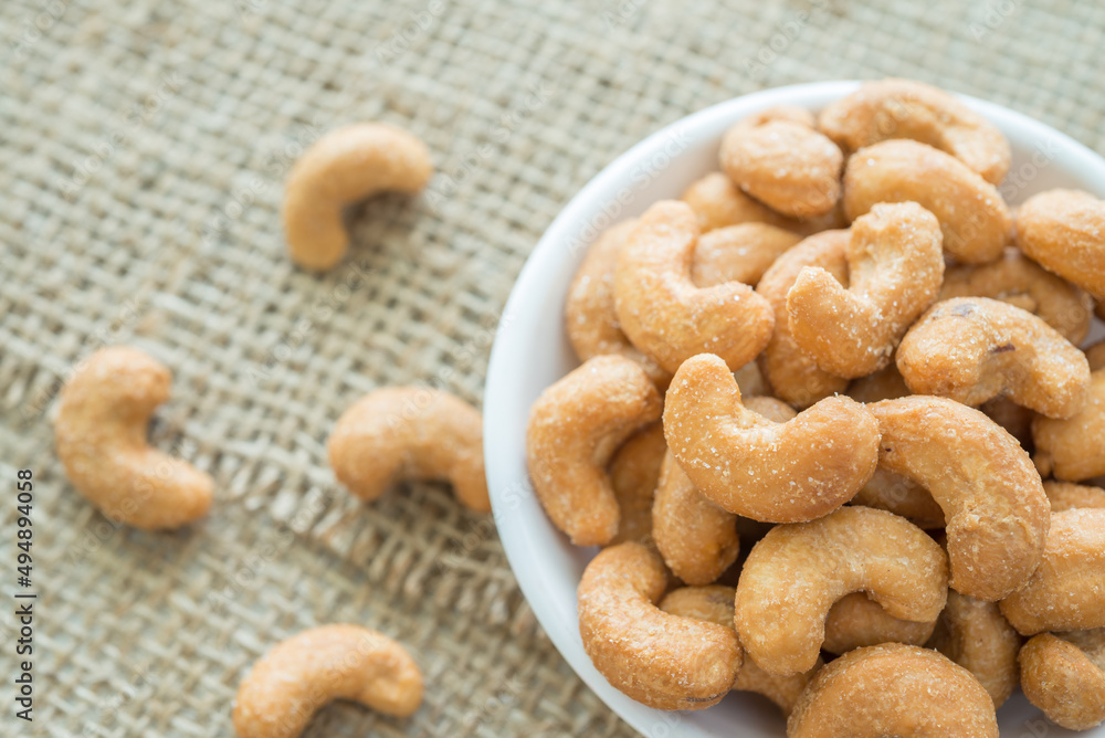 Salted cashew nuts in dessert bowl on sackcloth background. Salted cashew nuts in dessert bowl on sackcloth background.
