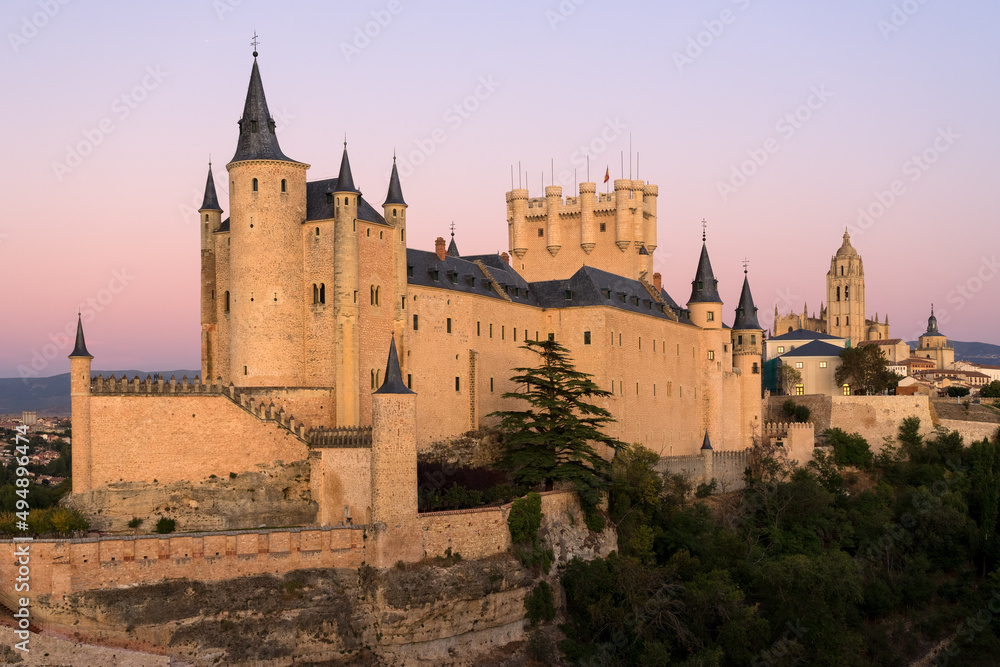View of the Alcazar fortress and St Mary cathedral of segovia with alpenglow in the background, listed world Heritage centre by UNESCO