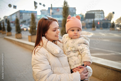 Mother holding baby smiling to camera. Real life authentic casual mom looking to camera holding