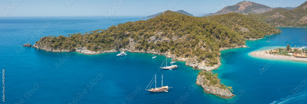 panorama of long cliff and sambar with yachts and beach in summer day in Turkey