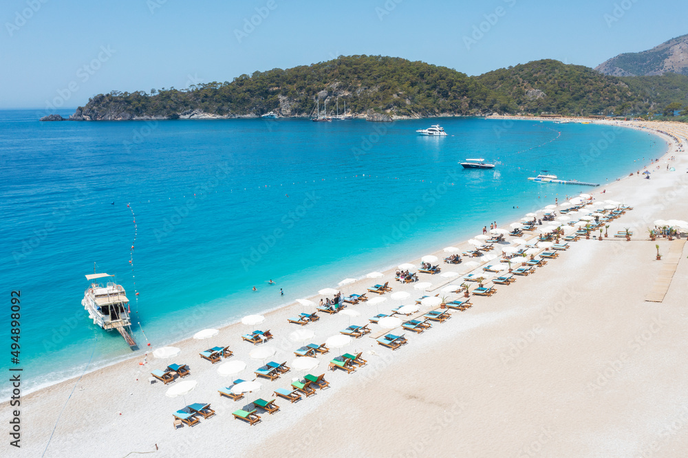 view to long beach with umbrellas and speed boat in summer day in Turkey