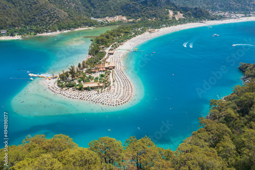 view to forest and long tail of sand bar and beach on it in emerald water of the bay in Turkey