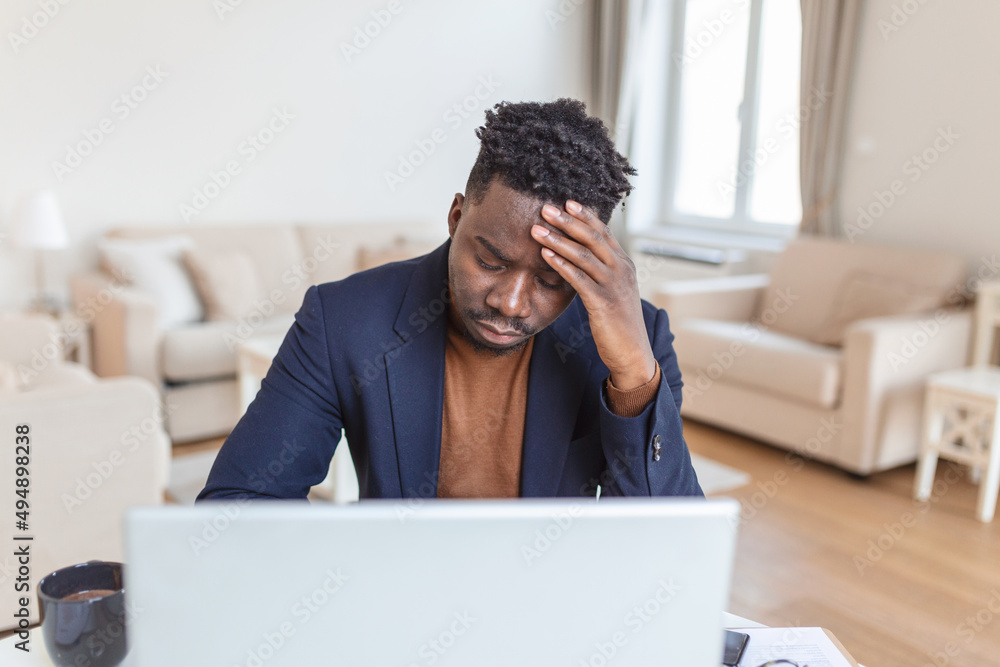 Stressed tired African American man touching temples, suffering from headache after long hours work, overworked overwhelmed businessman sitting at desk, feeling unwell Stressed tired African American man touching temples, suffering from headache after long hours work, overworked overwhelmed businessman sitting at desk, feeling unwell