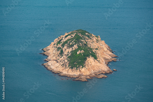 Small bare island surrounded by blue sea
