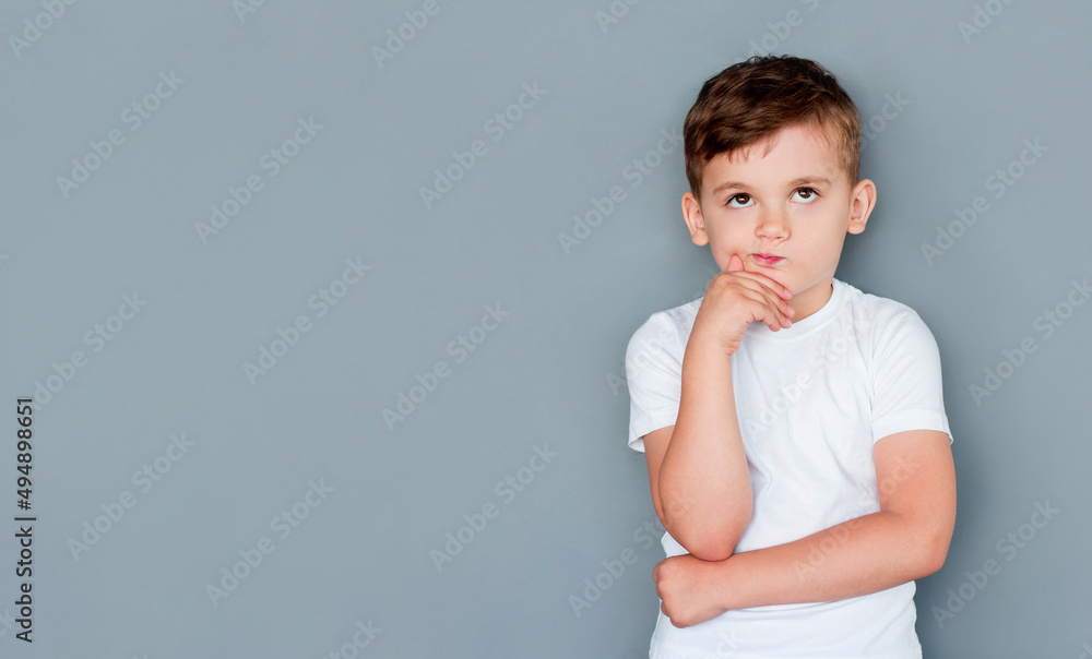 Emotional thinking little boy in casual outfit on gray background Emotional thinking little boy in casual outfit on gray background