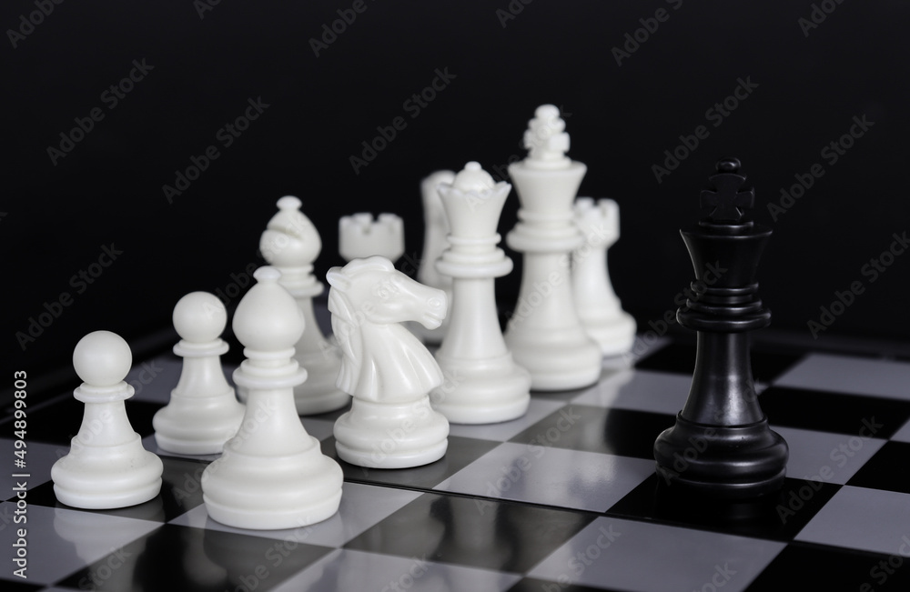 The king in a battle chess game stands on a chessboard with a black isolated background. Business Leadership Ideas.