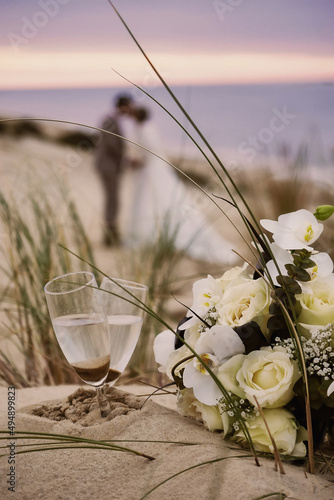 Romantic moment on the beach, champagne, newlyweds kissing in the distance/Moment romantique sur la plage, champagne, mariés qui s'embrassent au loin photo