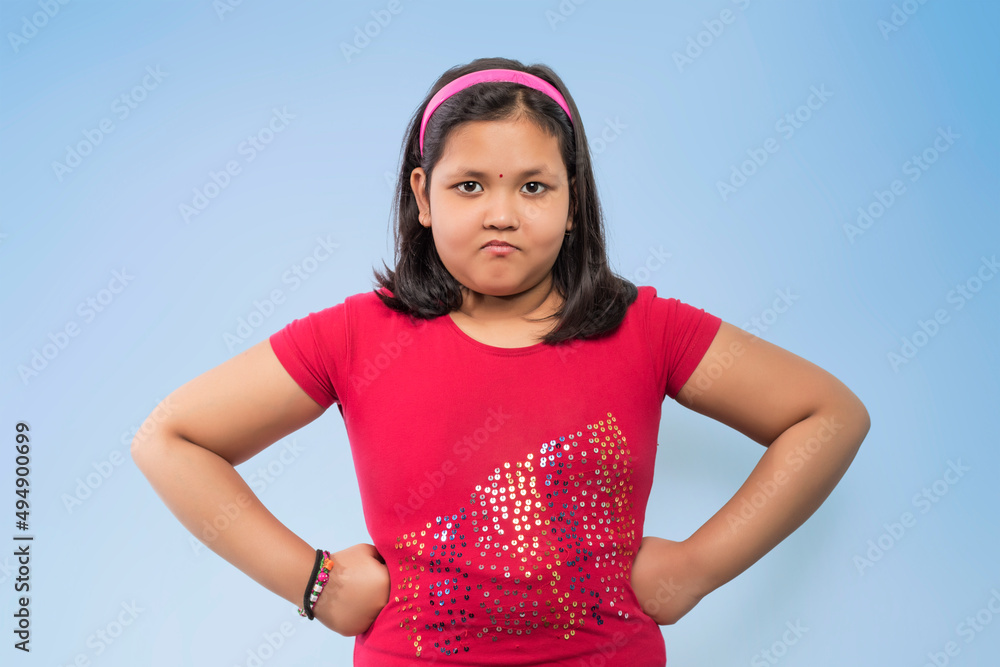 Portrait of an angry girl looking at camera isolated on a Blue background Portrait of an angry girl looking at camera isolated on a Blue background