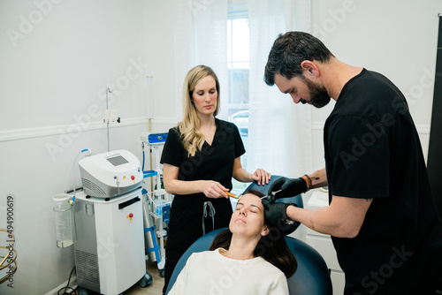 Canvas-taulu A woman getting botulinum toxin or fillers on her forehead and face by a doctor