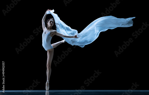 Beauty. Classic ballerina dancing with weightless fabric isolated on black studio background in neon. Theater, art, grace, action and motion concept.