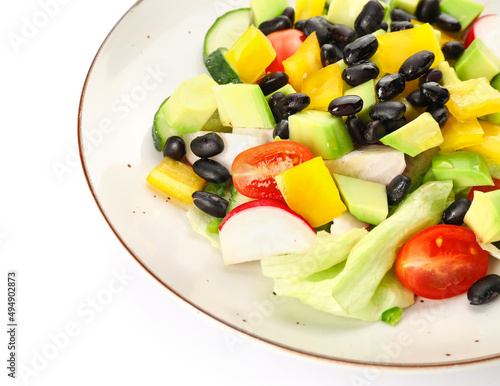 Plate of Mexican vegetable salad with black beans and radish on white background, closeup