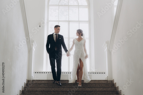 Wedding of a beautiful, stylish couple, a bride in a white wedding dress and a groom in a black suit, tuxedo.