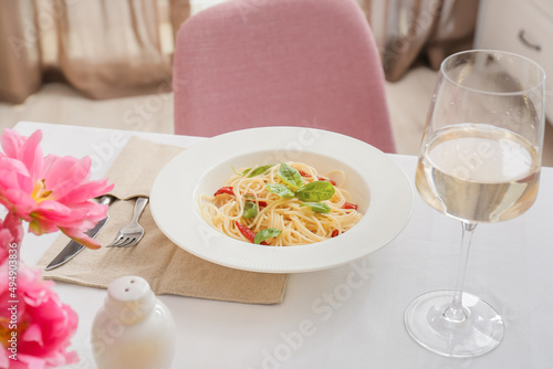Plate with delicious pasta and glass of wine on table in restaurant