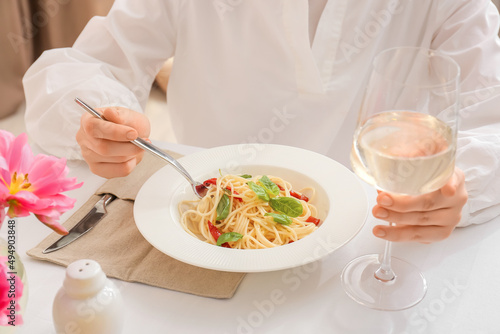 Woman eating delicious pasta at table in restaurant, closeup