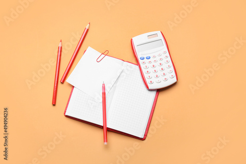 Notebook, pen, pencils and calculator on color background