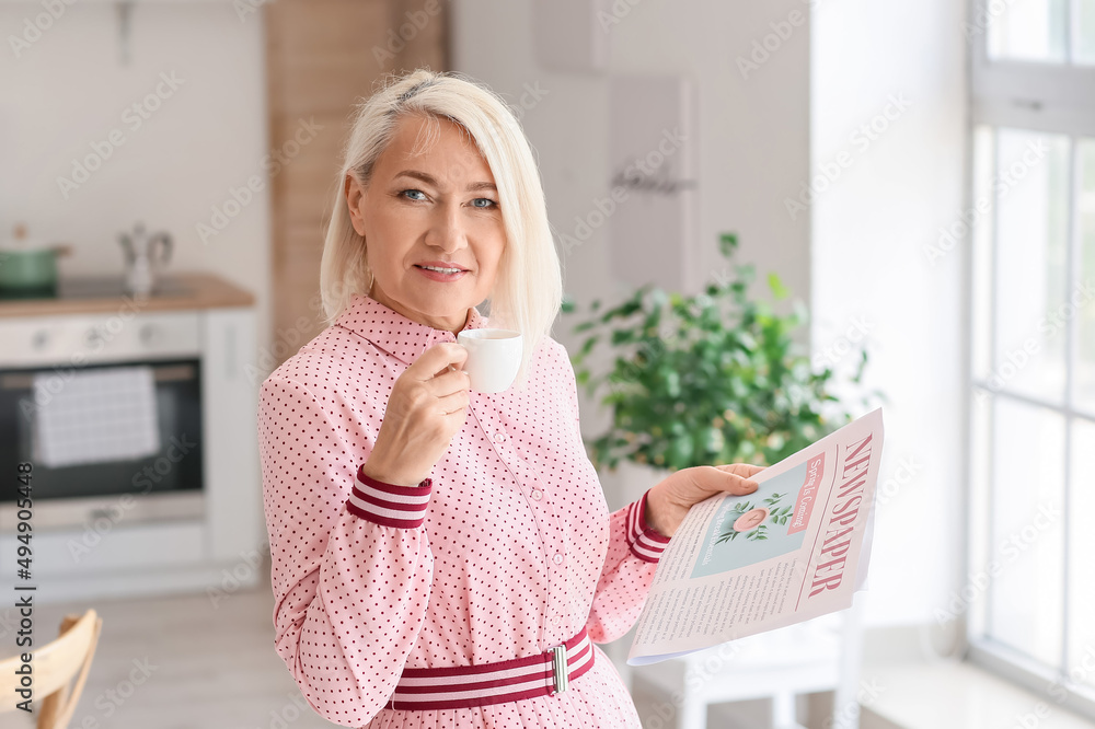Beautiful mature woman with cup of coffee reading newspaper at home Beautiful mature woman with cup of coffee reading newspaper at home