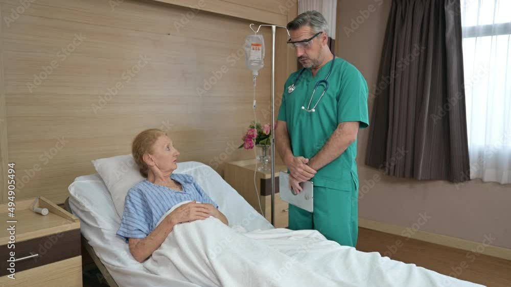 Doctor with laptop visiting and discussing the elderly female patient with IV fluids bag at hospital Doctor with laptop visiting and discussing the elderly female patient with IV fluids bag at hospital