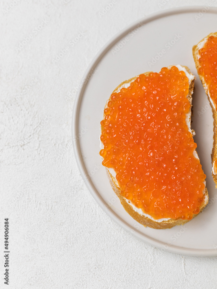 Toast with red caviar and cream cheese on a plate on a white background, close up Toast with red caviar and cream cheese on a plate on a white background, close up