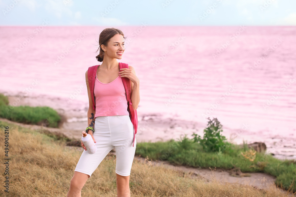 Young tourist with backpack near pink lake