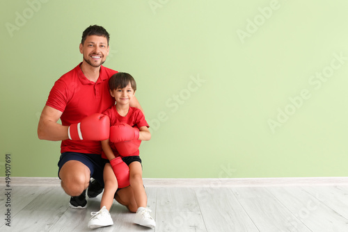 Little boy with boxing trainer near green wall