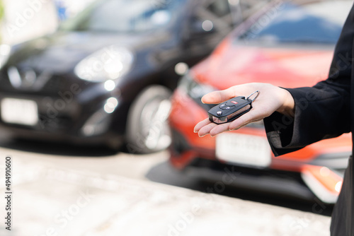 Close-up of dealer handing keys to new owners at a car show Automotive business Car sales Agreement Concept Female car salesman handing over new car keys