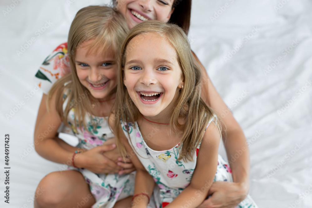 Happy mother and children of the twins sitting on the bed Happy mother and children of the twins sitting on the bed