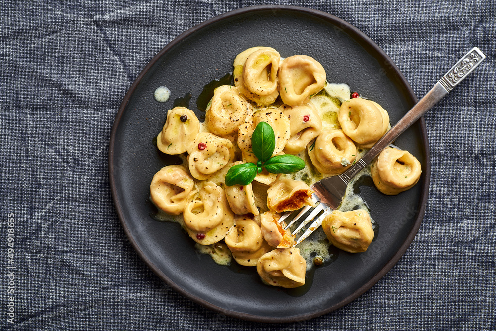 Tortellini ravioli creamy pasta. Italian ravioli pasta with pumpkin and basil on rustic background Tortellini ravioli creamy pasta. Italian ravioli pasta with pumpkin and basil on rustic background