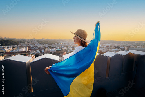 A woman stands with the national Ukrainian flag and waving it praying for peace at sunset in Lviv..A symbol of the Ukrainian people, independence and strength. Pray for Ukraine.