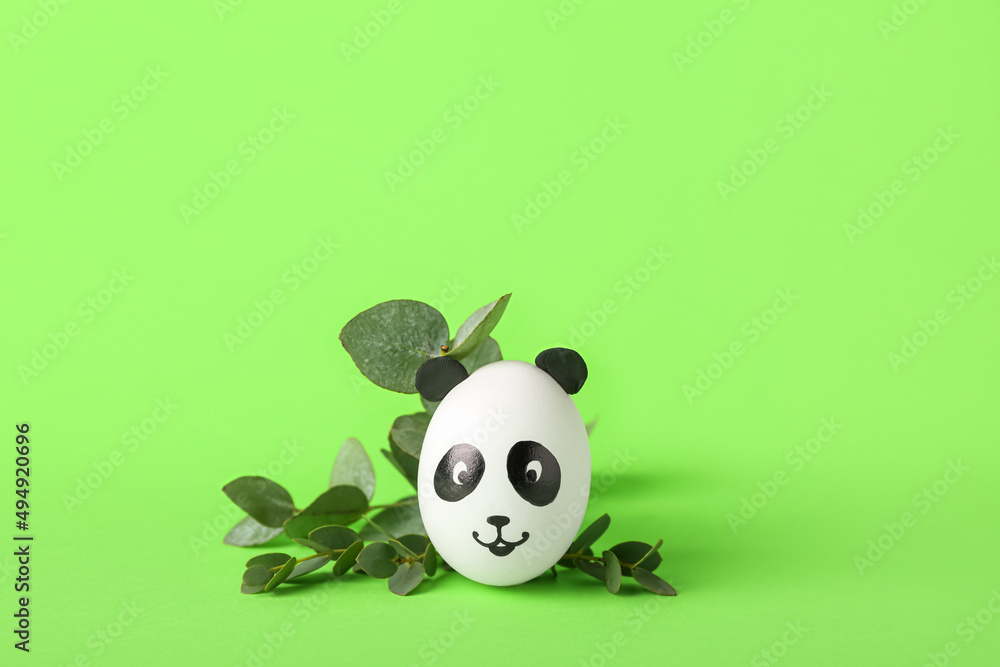 Fototapeta premium Creative painted Easter egg and branch on green background