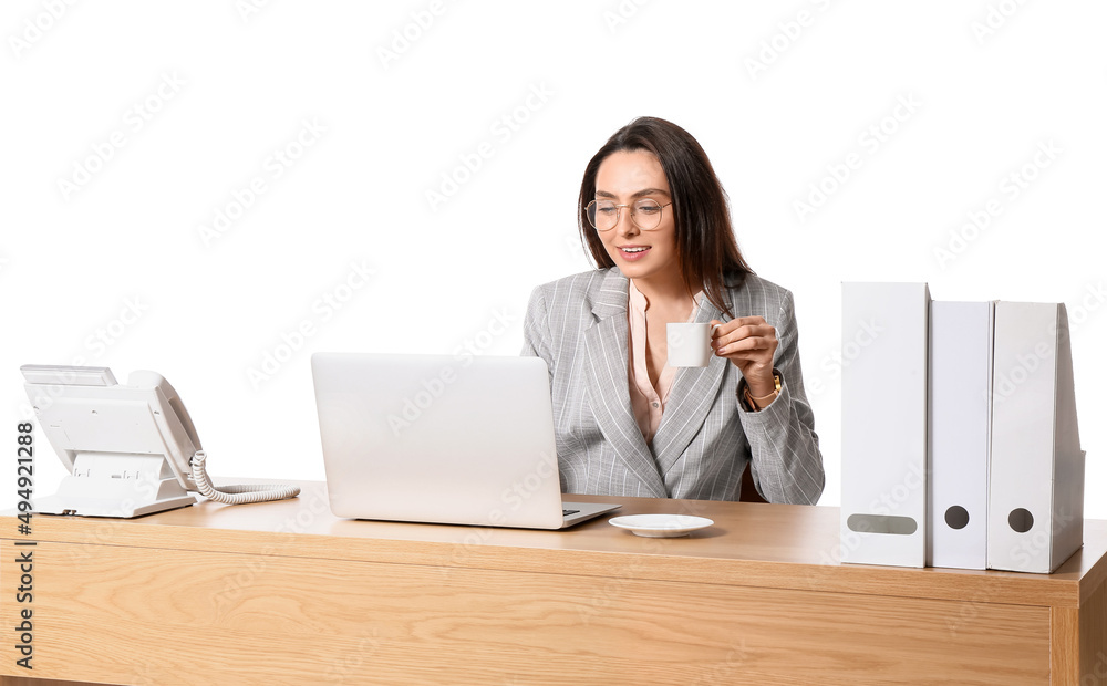 Young secretary with laptop drinking coffee at table on white background Young secretary with laptop drinking coffee at table on white background