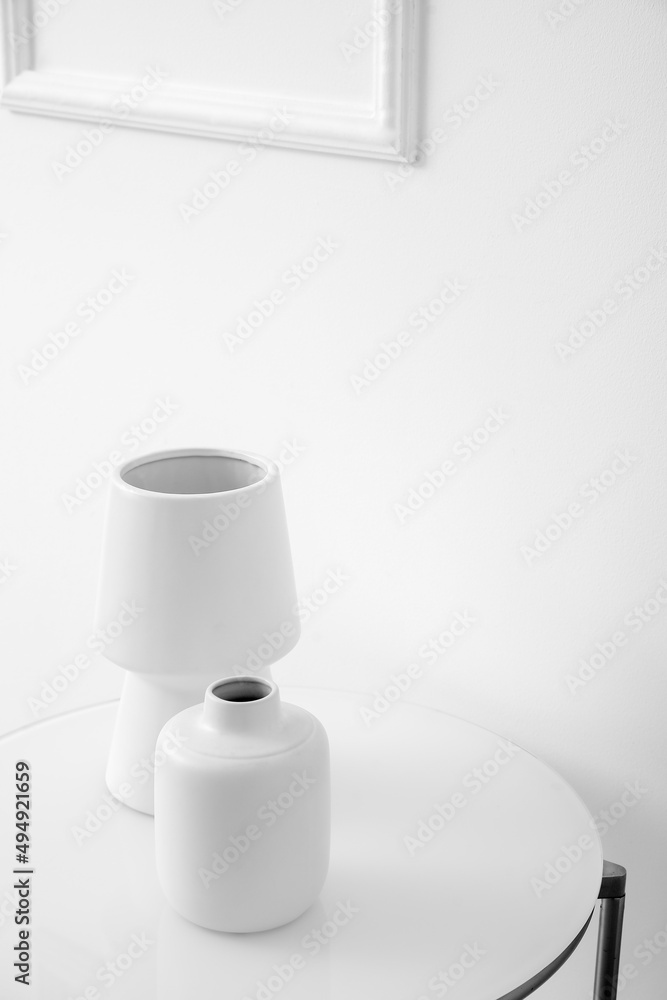 White vases on table near light wall White vases on table near light wall