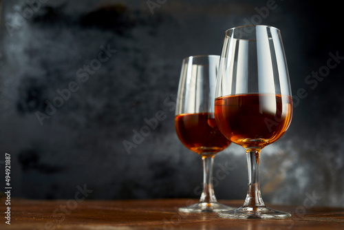 Photo Shiny wineglasses with sherry drink laced on wooden counter