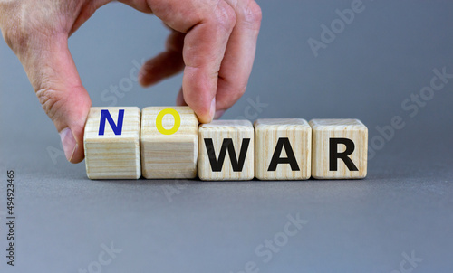No war symbol. Businessman turns cubes and changes concept words War to No war. Beautiful grey table grey background. Business and no war concept. Copy space.