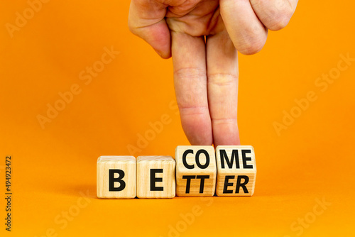 Become better symbol. Businessman turns wooden cubes and changes the concept word Better to Become. Beautiful orange table orange background. Business become better concept. Copy space. photo