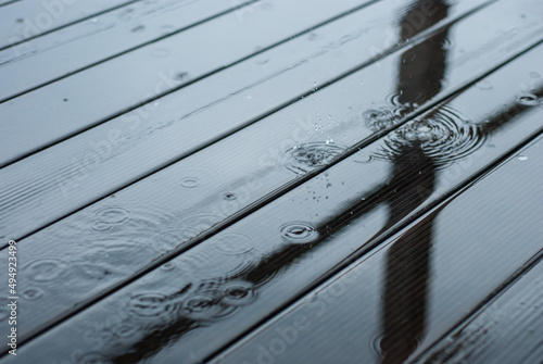 Raindrops fall on a wooden terrace. It's raining heavily. A puddle of water on the floor.