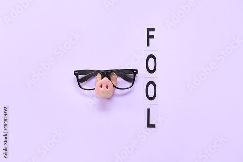 Composition with eyeglasses, pig nose and word FOOL on color background. April Fools Day celebration