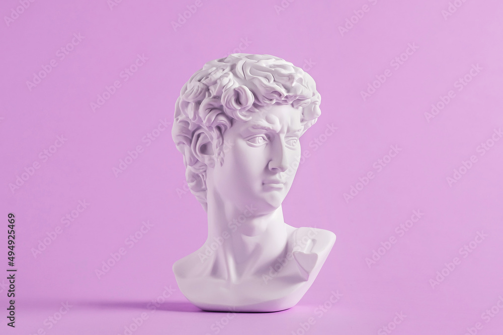 Ancient statue is head of David on purple background. - obrazy, fototapety, plakaty 