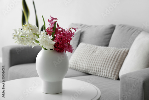 Vase with beautiful hyacinth flowers on table in living room