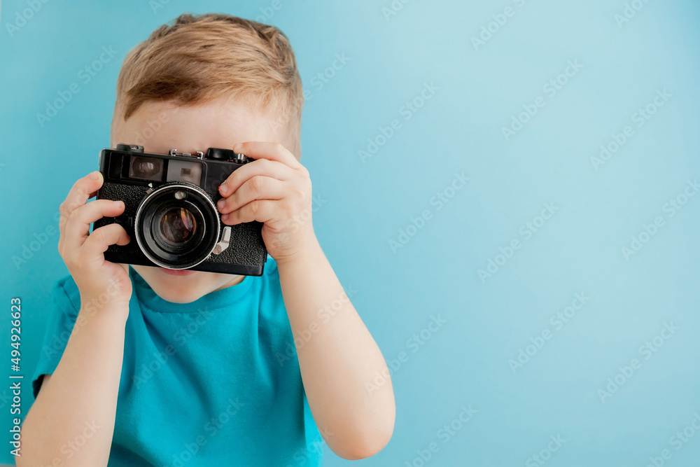 Little boy with an old camera on a blue background Little boy with an old camera on a blue background