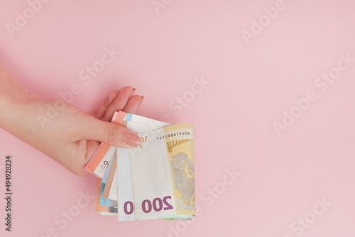 Euro banknotes money in female hands on pink background