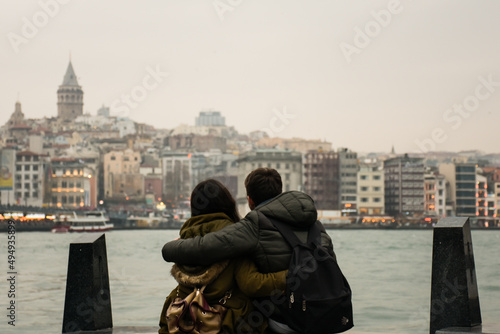 two lovers girl and boy sitting against galata tower in bosphorus istanbul near the sea